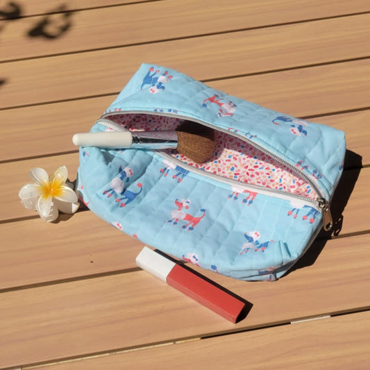 Small blue pouch with floral pattern on a wooden surface with a flower and lipstick.
