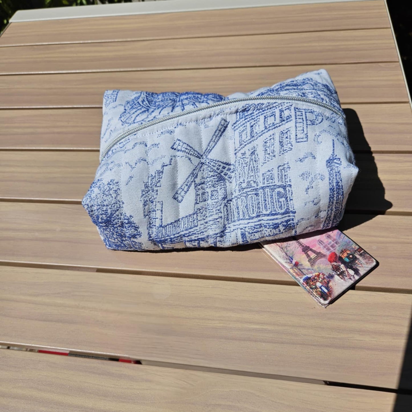Blue and white patterned bag on a wooden surface with a card beside it