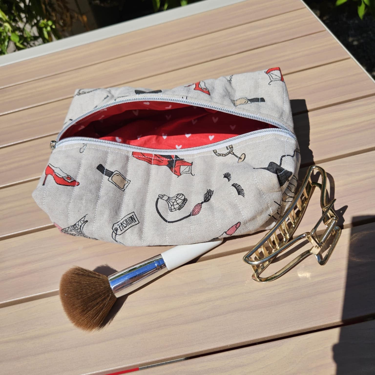Makeup bag with cartoon designs on a wooden surface with a brush and keychain.