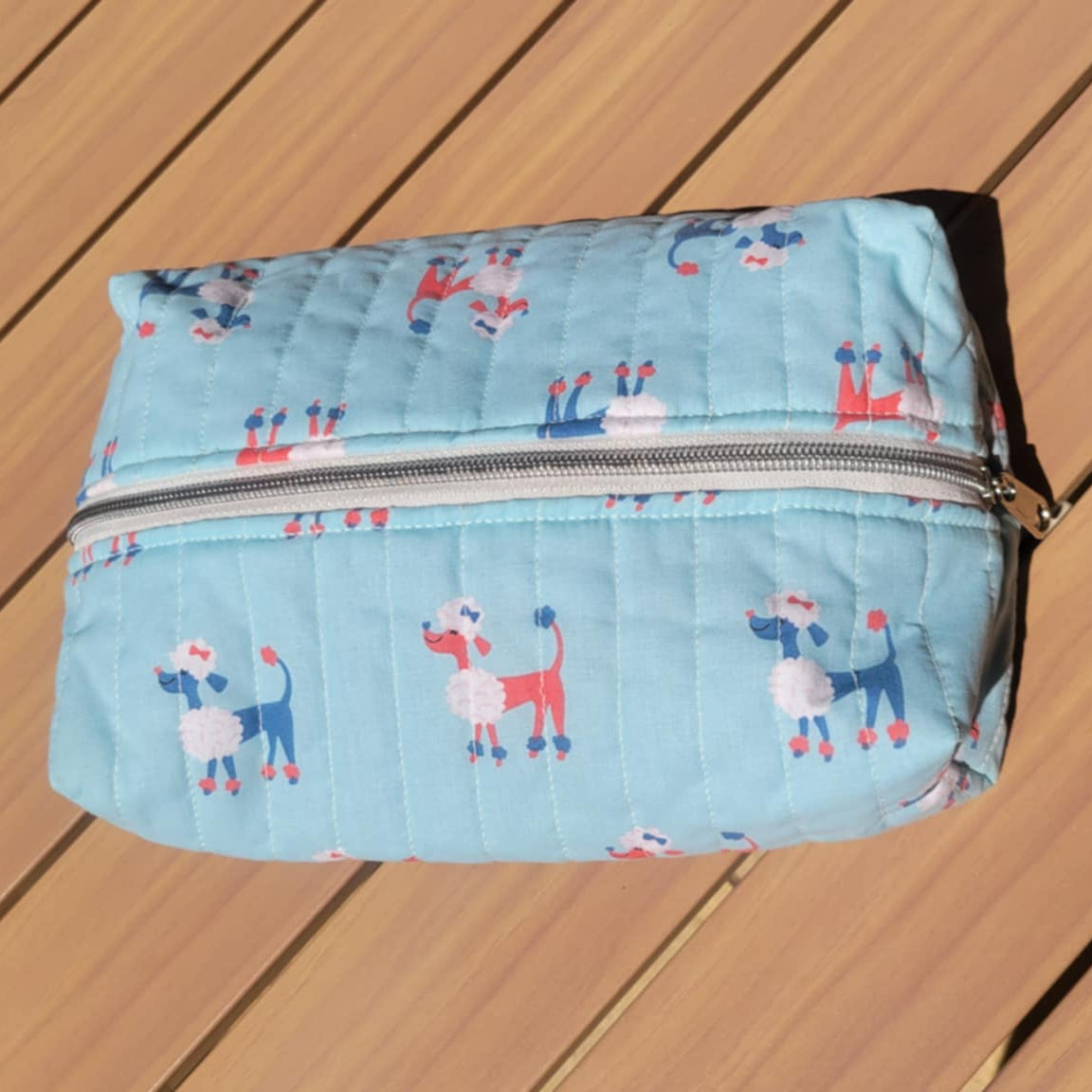 Light blue quilted pouch with animal pattern on a wooden surface