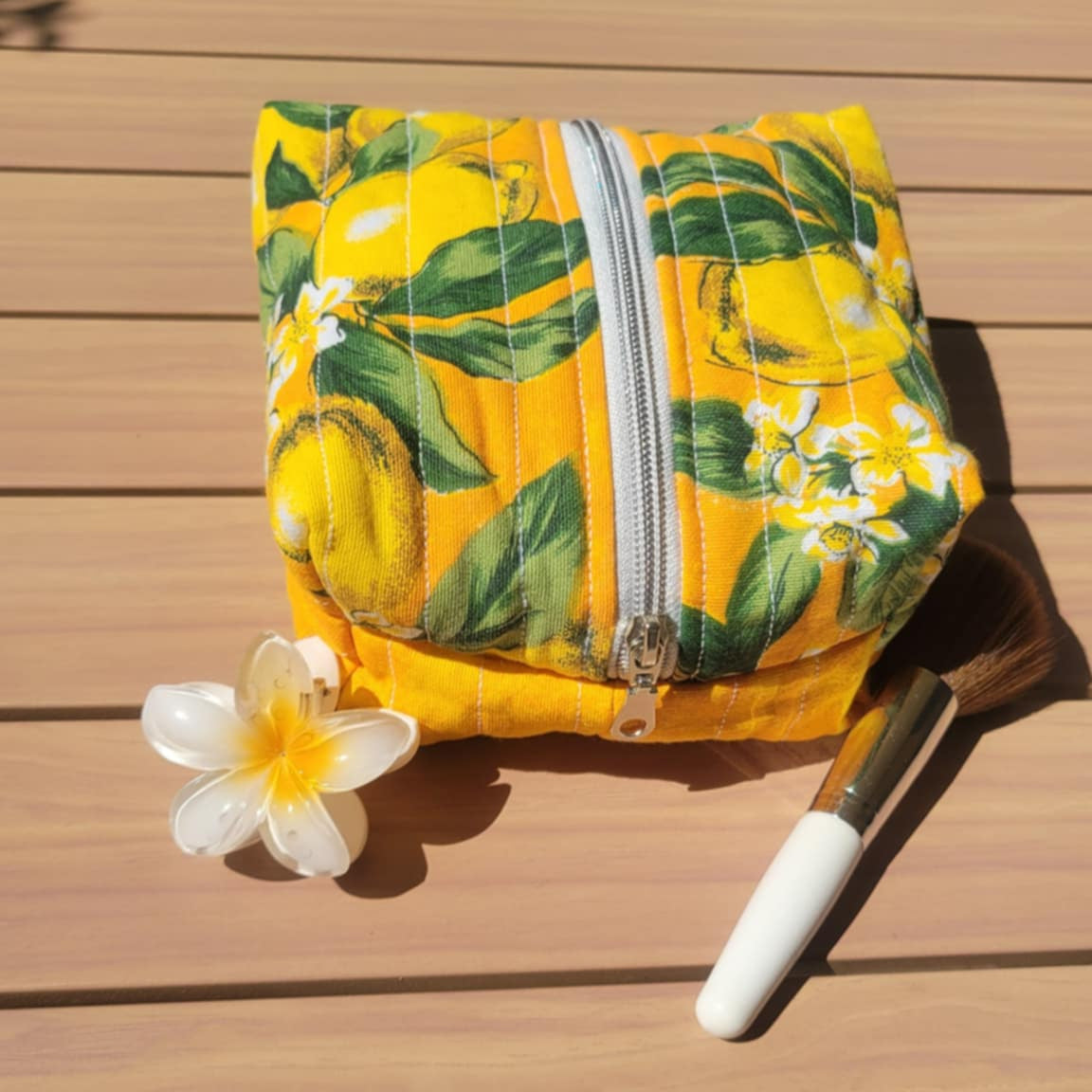 Yellow floral-patterned pouch on a wooden surface with a white flower and knife.