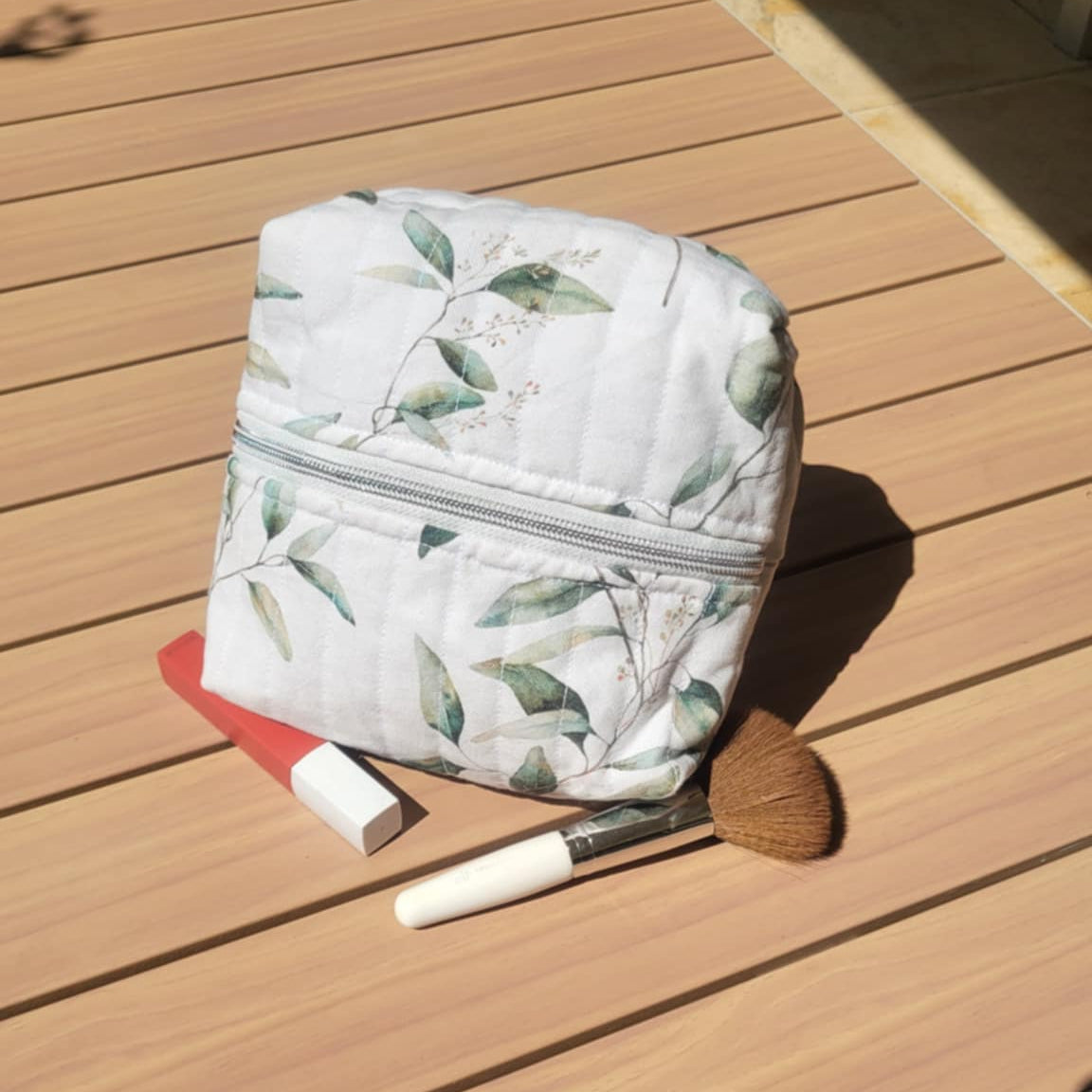 Cosmetic bag with makeup items on a wooden surface