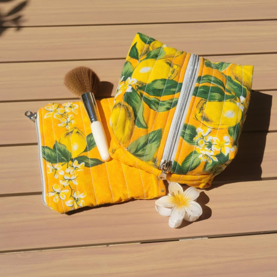 Yellow floral-patterned pouch with a white flower on a wooden surface