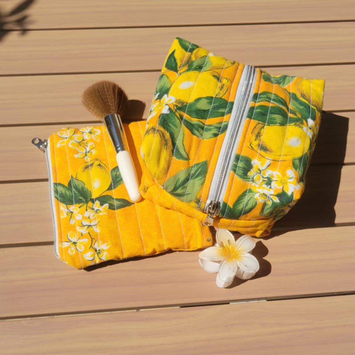 Yellow floral-patterned pouch with a white flower on a wooden surface