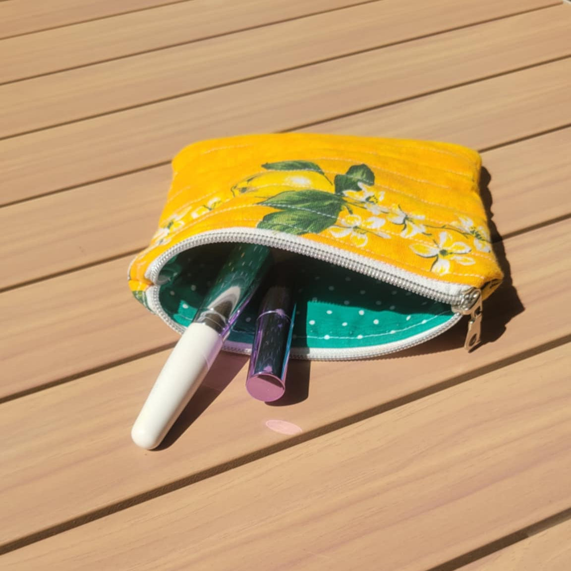Yellow pouch with makeup items on a wooden surface