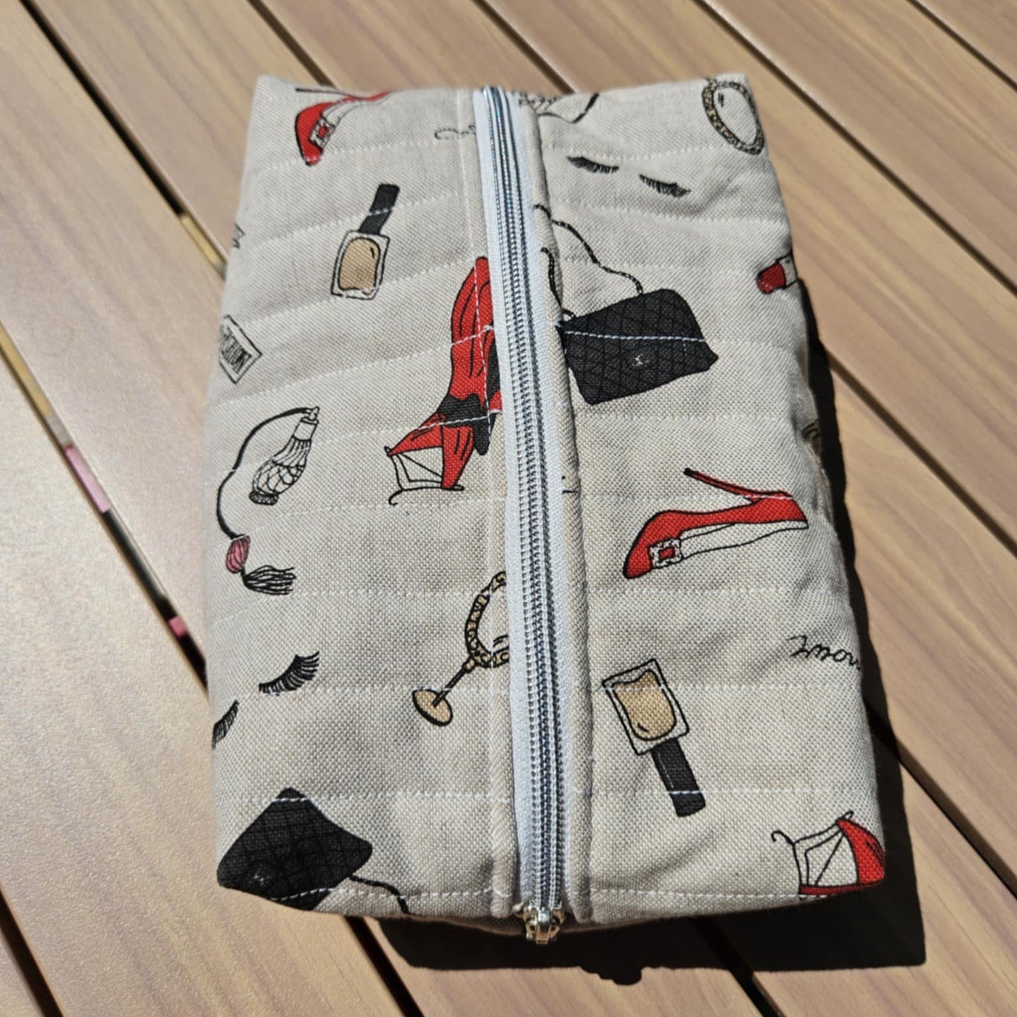 Fabric pouch with zipper and fashion-themed pattern on a wooden surface