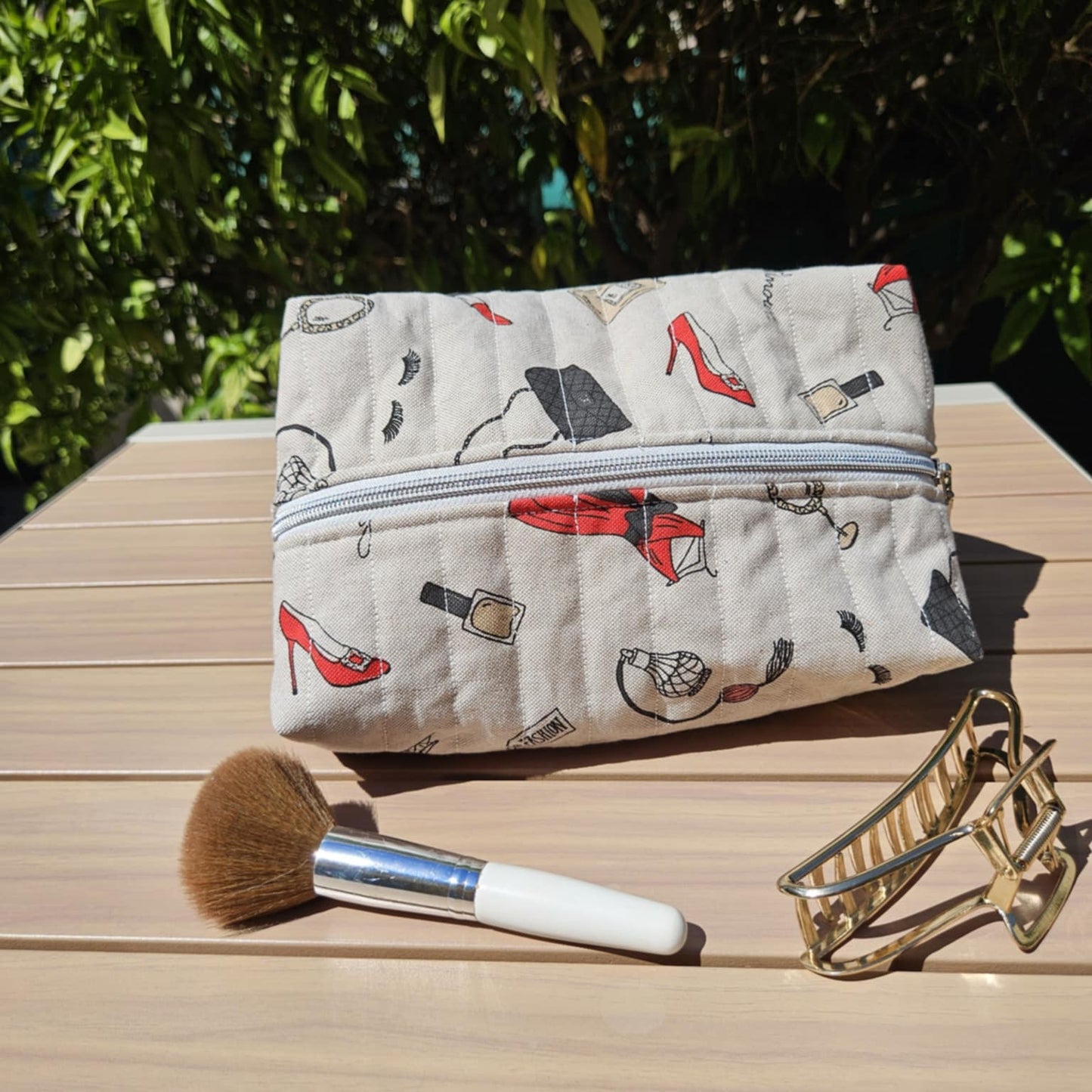 Makeup bag with cosmetic items on a wooden surface outdoors