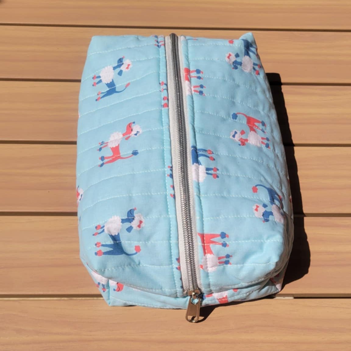 Light blue pouch with animal pattern on a wooden surface
