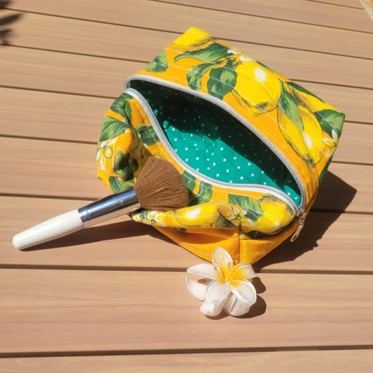 Yellow patterned pouch with a white flower on a wooden surface