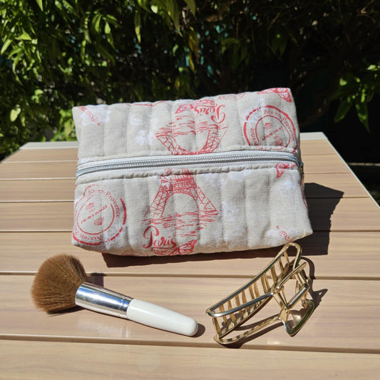 Makeup pouch with a brush and hairbrush on a wooden surface outdoors