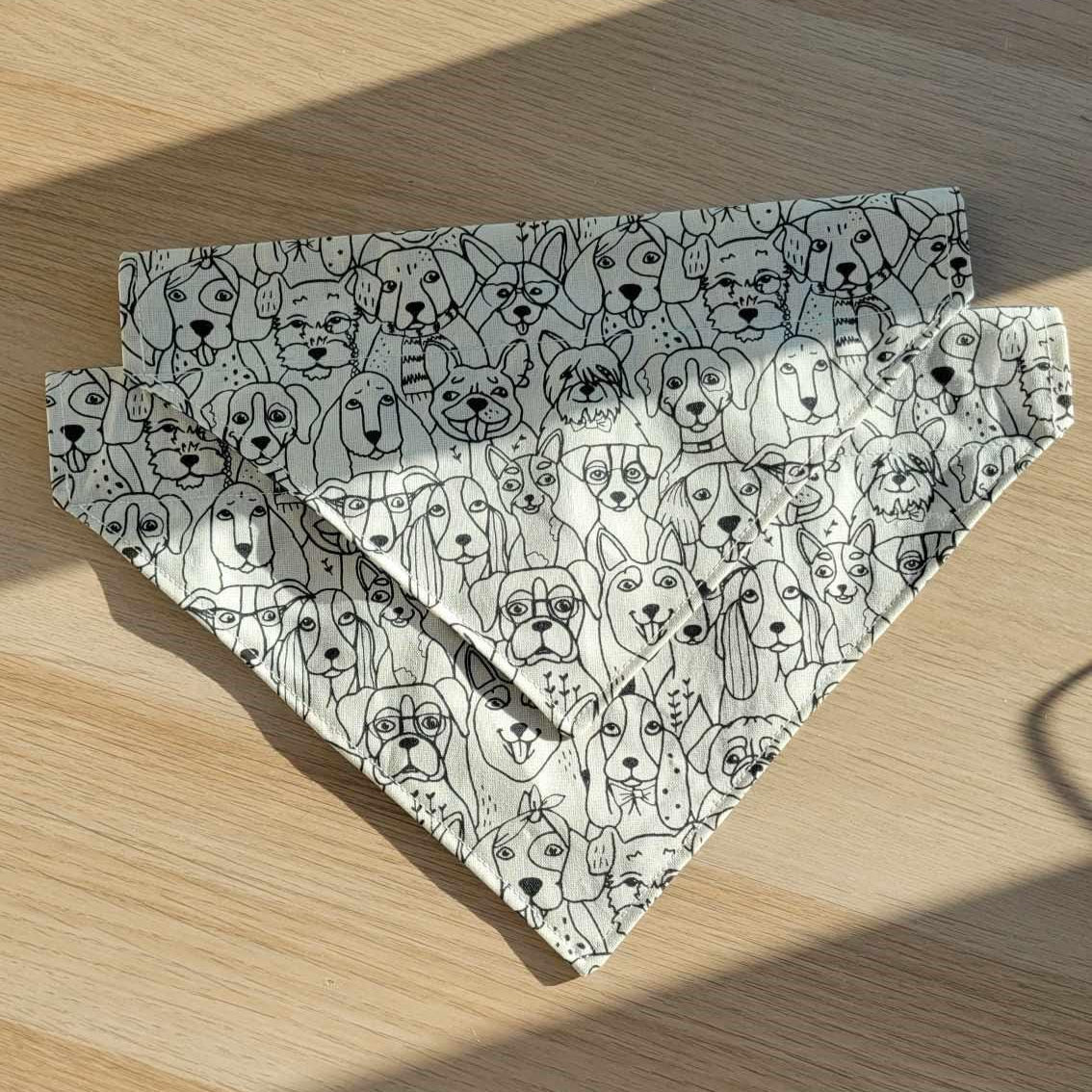 Handmade reversible dog bandana with a black and white dog face pattern on one side and navy with white hearts on the other. Slides onto collar. Currently available in two sizes.