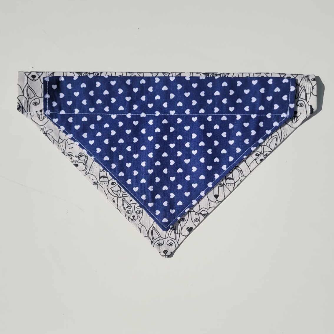 Handmade reversible dog bandana with a black and white dog face pattern on one side and navy with white hearts on the other. Slides onto collar. Available in small and medium.