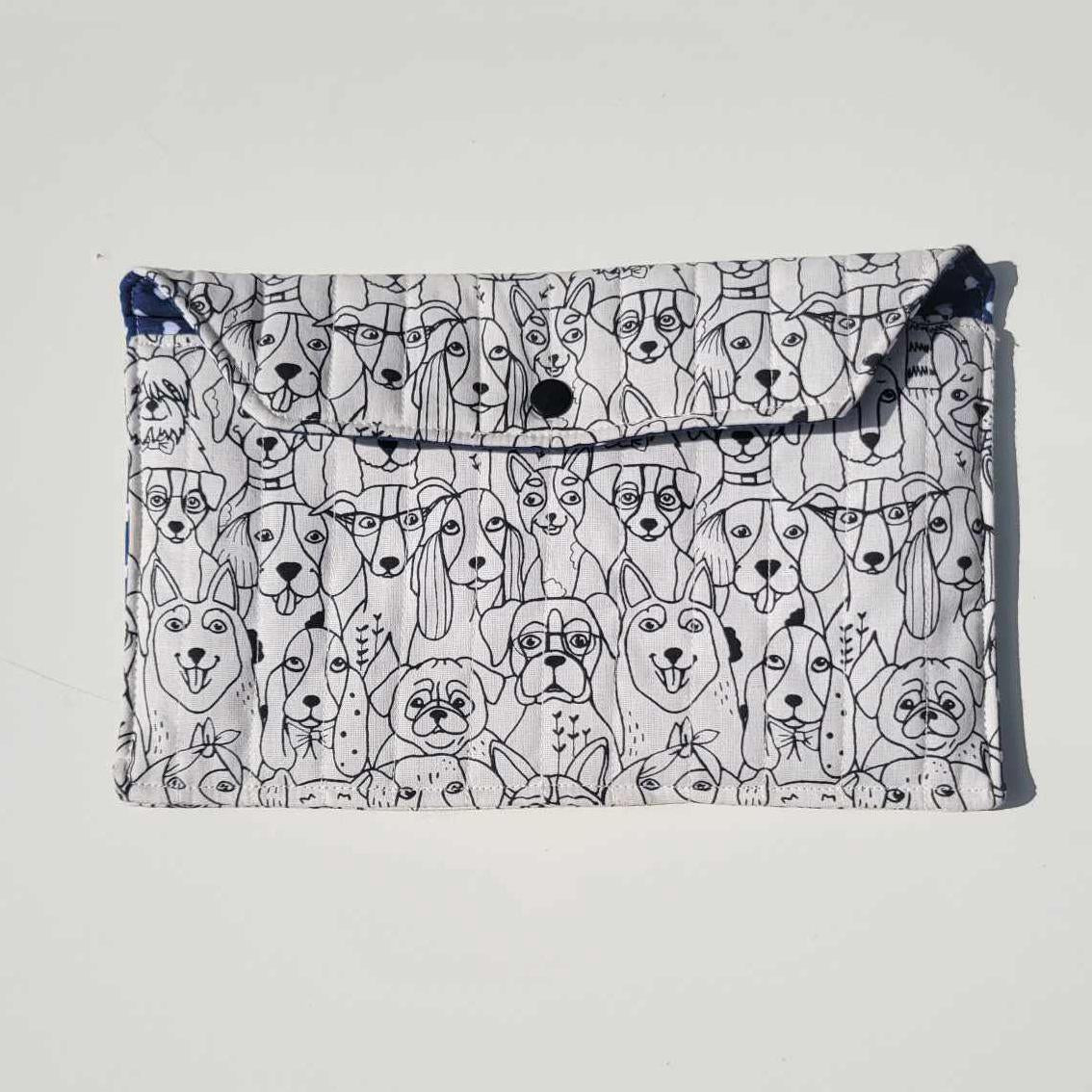 Handmade e-reader or document holder with a black and white dog print for the exterior fabric and a navy blue and white heart fabric for the interior. It is lightly quilted with a snap closure.