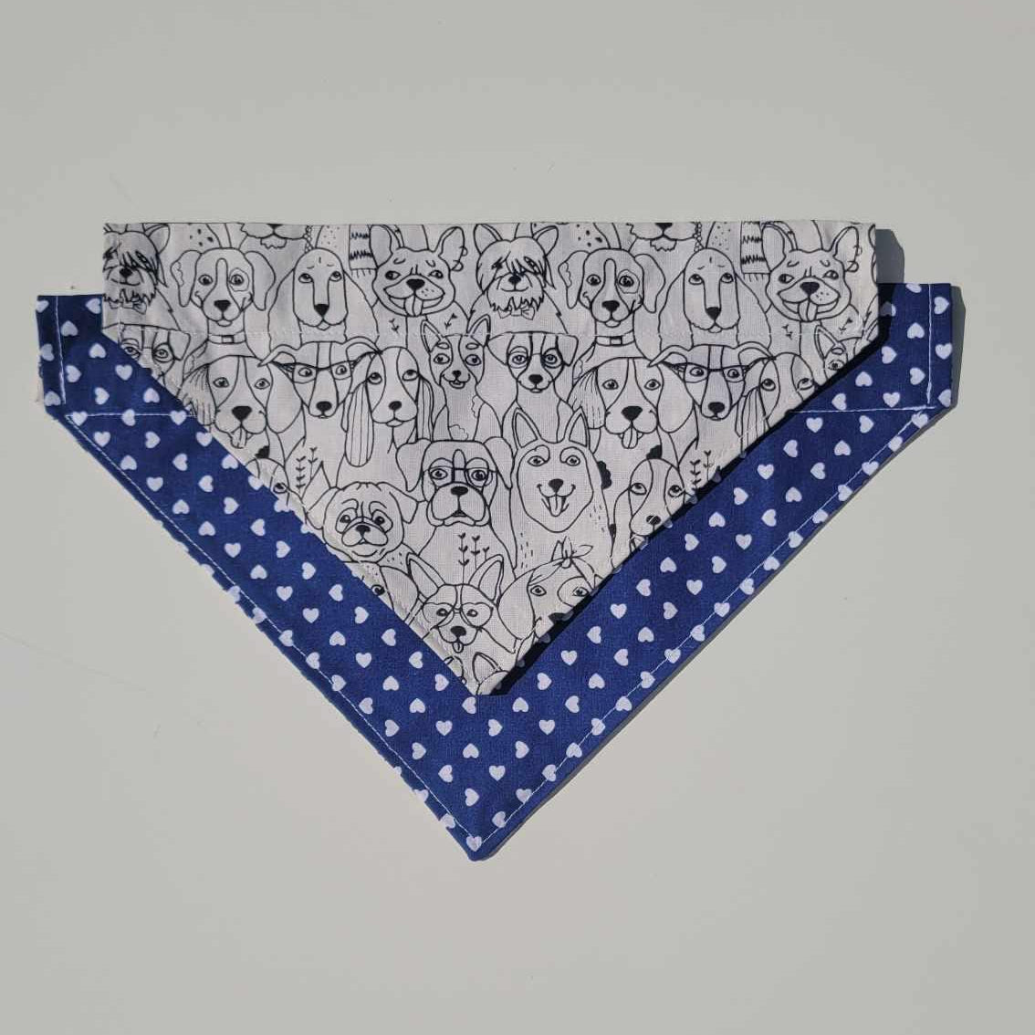 Handmade reversible dog bandana with a black and white dog face pattern on one side and navy with white hearts on the other. Slides onto collar. Available in small and medium.